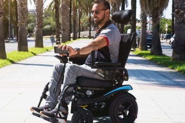 Robiący sobie selfie uśmiechnięty mężczyzna na wózku elektrycznym.