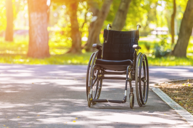 Wózek inwalidzki stojący na alejce parkowej.