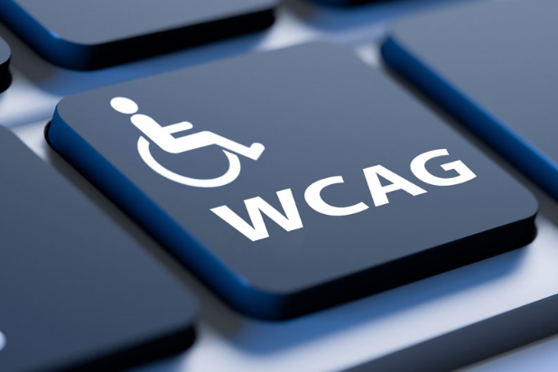 Na pierwszym planie czarny klawisz z klawiatury komputera z symbolem osoby na wózku i symbolem WCAG.