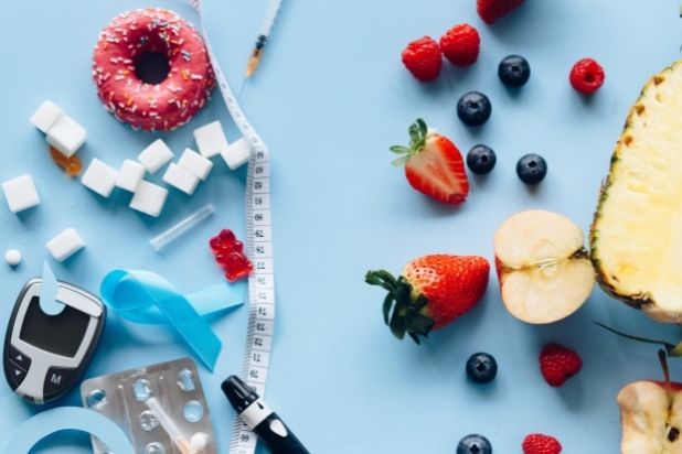 Grafika podzielona centymetrem na dwie części. Po Lewej tronie znajduje się glukometr, kostki cukru, słodycze, niebieska wstążeczka symbolizująca cukrzycę oraz tabletki. Po prawej stronie grafiki mamy strzykawkę oraz owoce. Po środku pen do insuliny.
