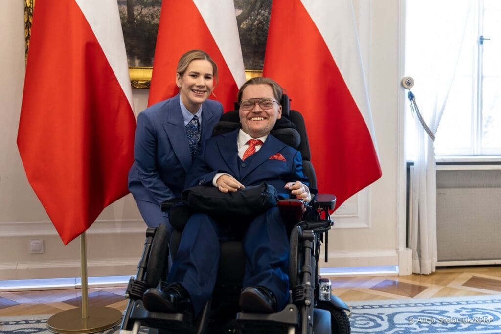 Jakub Gietka z Małżonką Prezydenta RP, w tle flagi Polski